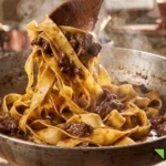 Mantecatura finale a fuoco vivo delle pappardelle fresche avvolte dal ricco ragù di lepre